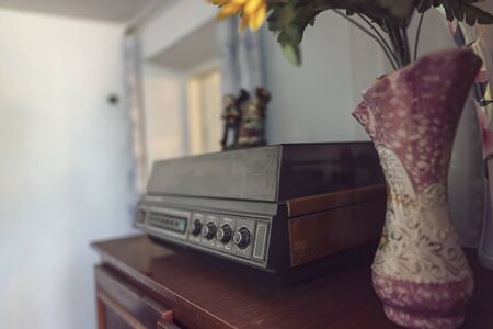 An old vinyl record player with wooden cases stands on a chest of drawers of the same eraの写真素材