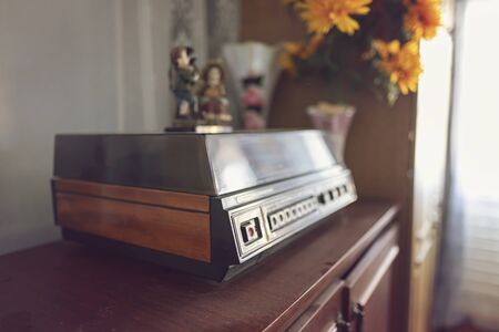 An old vinyl record player with wooden cases stands on a chest of drawers of the same eraの写真素材
