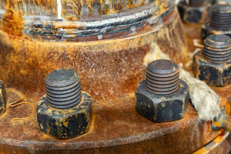 The cover of the old rusty heat exchanger covered with the same rusty bolts and nuts of large sizes