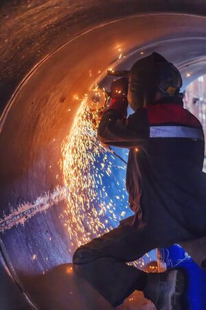 Sparks from the grinding machine fly during processing of the weld