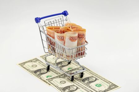 In a toy grocery cart rolled banknotes in 5000 rubles, the bottom are dollar billsの写真素材