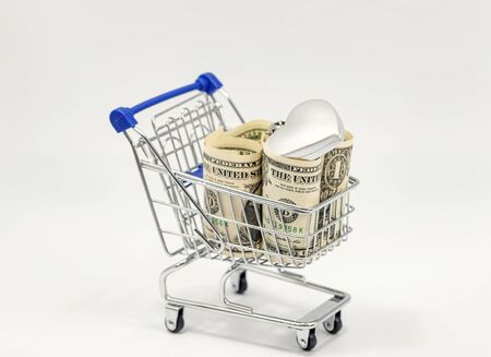In a toy grocery cart are rolled up dollars and Christmas decorationsの写真素材