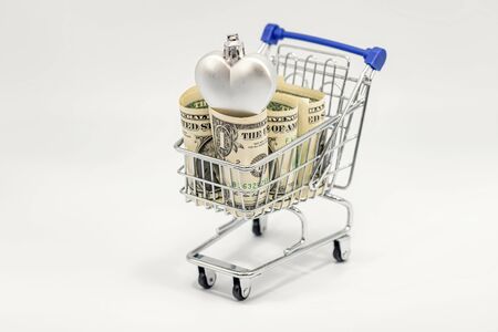 In a toy grocery cart are rolled up dollars and Christmas decorationsの写真素材