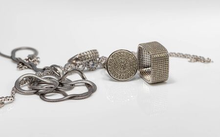 Different in shape silver rings with cubic Zirconia, silver bracelet and chain with elegant weaving on white reflect surfaceの写真素材