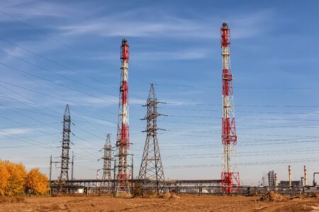 Two identical high torches for burning residues of petroleum products are painted in red and whiteの写真素材