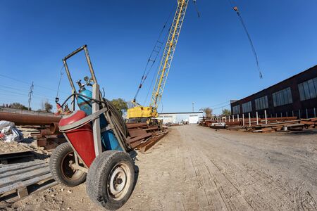 Cart with cylinders of liquefied gas for metal cutting on the background of a crane for loading metal structuresの写真素材