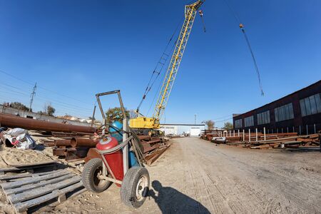 Cart with cylinders of liquefied gas for metal cutting on the background of a crane for loading metal structuresの写真素材