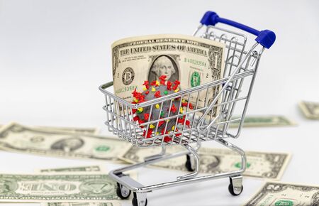 A coronavirus model and dollars in a toy shopping cartの写真素材