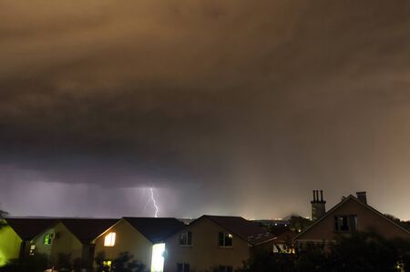 A flash of lightning against the evening sky and mountain ranges