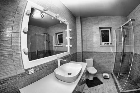 The interior of the bathroom with a big illuminated mirror, walk-in shower and elegant sinkの写真素材