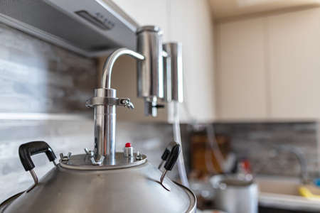 A large hooch with a thermometer stands on the gas stove in the spacious bright kitchenの写真素材