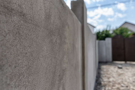 A stucco-lined fence wall, the front door is visible in the backgroundの写真素材