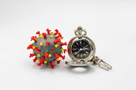 A plastic coronavirus model and a pocket watch lie on a white backgroundの写真素材