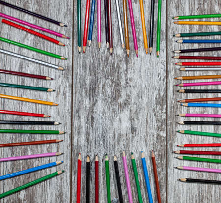 A frame of colored pencils is laid out on a wooden surface. Frame for writing text in the centerの写真素材