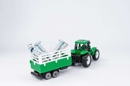 Toy green tractor carries various steel bolts and screws in the trailerの写真素材