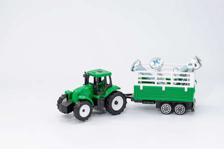 Toy green tractor carries various steel bolts and screws in the trailer