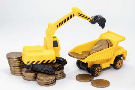 Toy construction bulldozer loads money into the back of a toy truckの写真素材