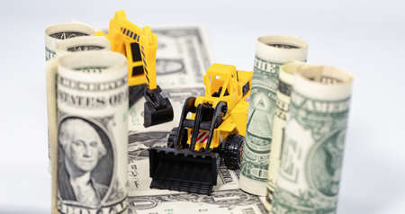 Toy construction bulldozer loads money into the back of a toy truckの写真素材