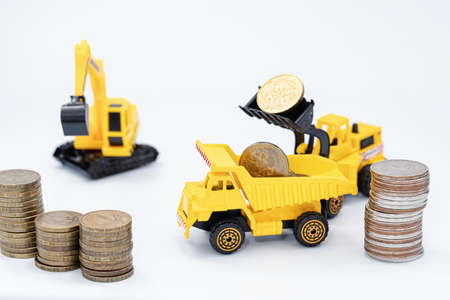 Toy construction bulldozer loads money into the back of a toy truck