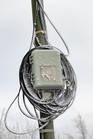 Wires power lines and optical communication lines with snow stuck on them and covered with ice after a snowfallの写真素材