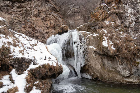 The waterfalls, which are not completely frozen in winter, flow down from the porous rocksの写真素材