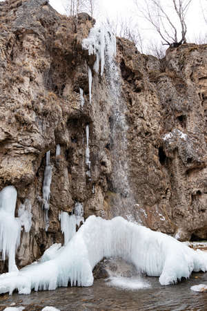 The waterfalls, which are not completely frozen in winter, flow down from the porous rocksの写真素材