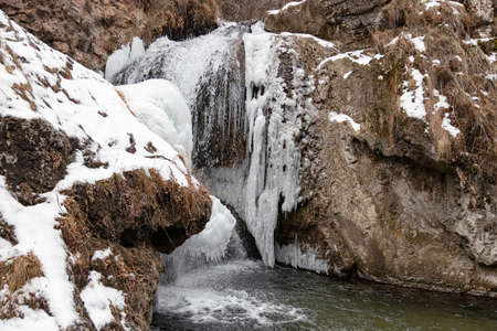 The waterfalls, which are not completely frozen in winter, flow down from the porous rocksの写真素材