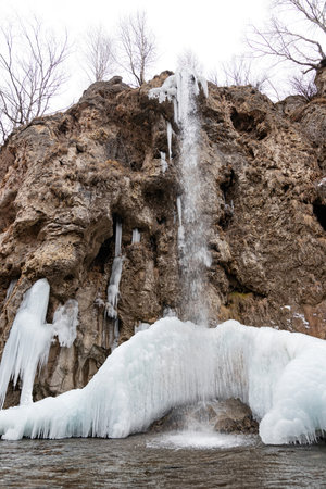 The waterfalls, which are not completely frozen in winter, flow down from the porous rocksの写真素材