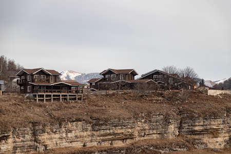 Wooden buildings of small private hotels stand on the edge of a cliff in a mountainous area
