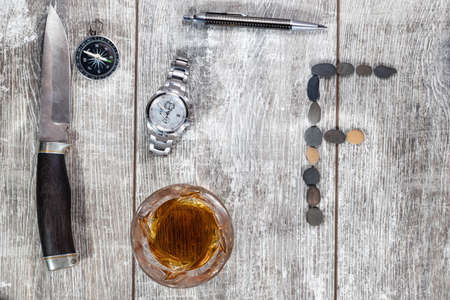 Men's items and accessories lie on a light wooden background. The letter F of the English alphabet is made of small stonesの写真素材