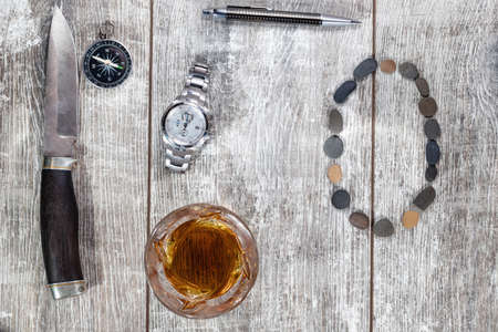 Men's items and accessories lie on a light wooden background. The letter O of the English alphabet is made of small stonesの写真素材
