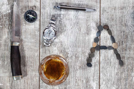 Men's items and accessories lie on a light wooden background. The letter A of the English alphabet is made of small stonesの写真素材