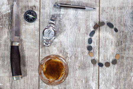 Men's items and accessories lie on a light wooden background. The letter C of the English alphabet is made of small stonesの写真素材