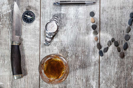 Men's items and accessories lie on a light wooden background. The letter W of the English alphabet is made of small stonesの写真素材