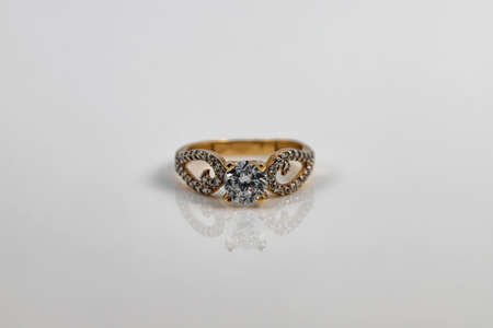 Women's gold ring with a large diamond is reflected on the white surfaceの写真素材