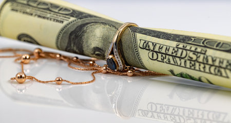 A hundred dollar bill rolled into a tube and inserted into a gold ring with a sapphireの写真素材
