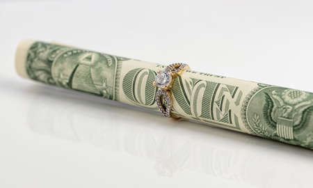 A one dollar bill rolled into a tube and inserted into a gold ring with a diamondの写真素材
