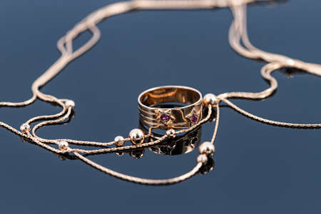 A wide gold ring with a bas relief in the shape of stars inlaid with rubies and a chain with large gold beadsの写真素材