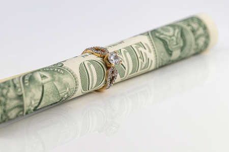 A one dollar bill rolled into a tube and inserted into a gold ring with a diamondの写真素材
