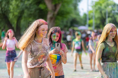 ESSENTUKI- JUNE 20: A girl with a painted face takes a selfie on her phone at the festival of colors. June 20, 2021 in Essentuki, Russia.のeditorial素材