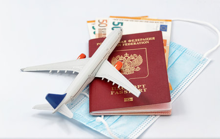 Protective medical masks, EURO, a passport, a model airplane and a 3D model of the virus lie nearbyの写真素材