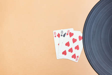 An old vinyl record and lucky three eights in cards on a beige backgroundの写真素材