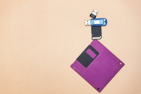 A floppy disk and modern media are lying next to each other. There is a place for text in the photoの写真素材