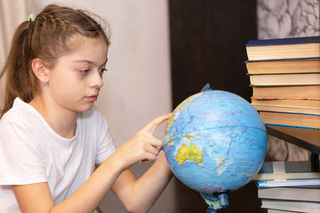 The girl looks at the globe with interest and finds on it unfamiliar countries for herself.の写真素材