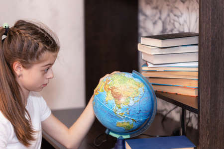 The girl looks at the globe with interest and finds on it unfamiliar countries for herself.の写真素材