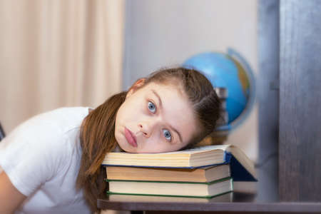 A middle school student is tired of homework and lies with her head on an open book.の写真素材