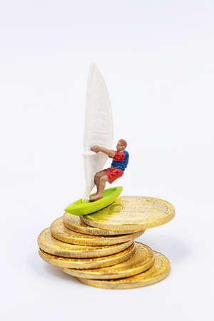 Toy wind surfer rides on bitcoin gold coins as on wavesの写真素材
