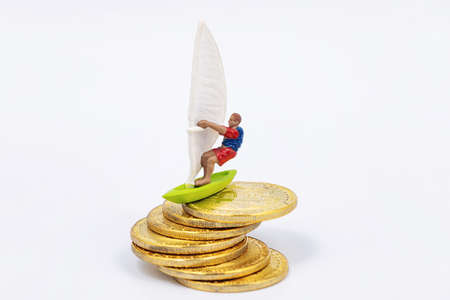 Toy wind surfer rides on bitcoin gold coins as on wavesの写真素材