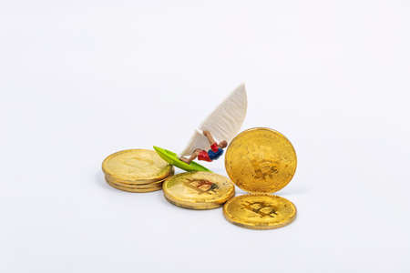 Toy wind surfer rides on bitcoin gold coins as on wavesの写真素材
