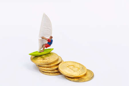Toy wind surfer rides on bitcoin gold coins as on wavesの写真素材